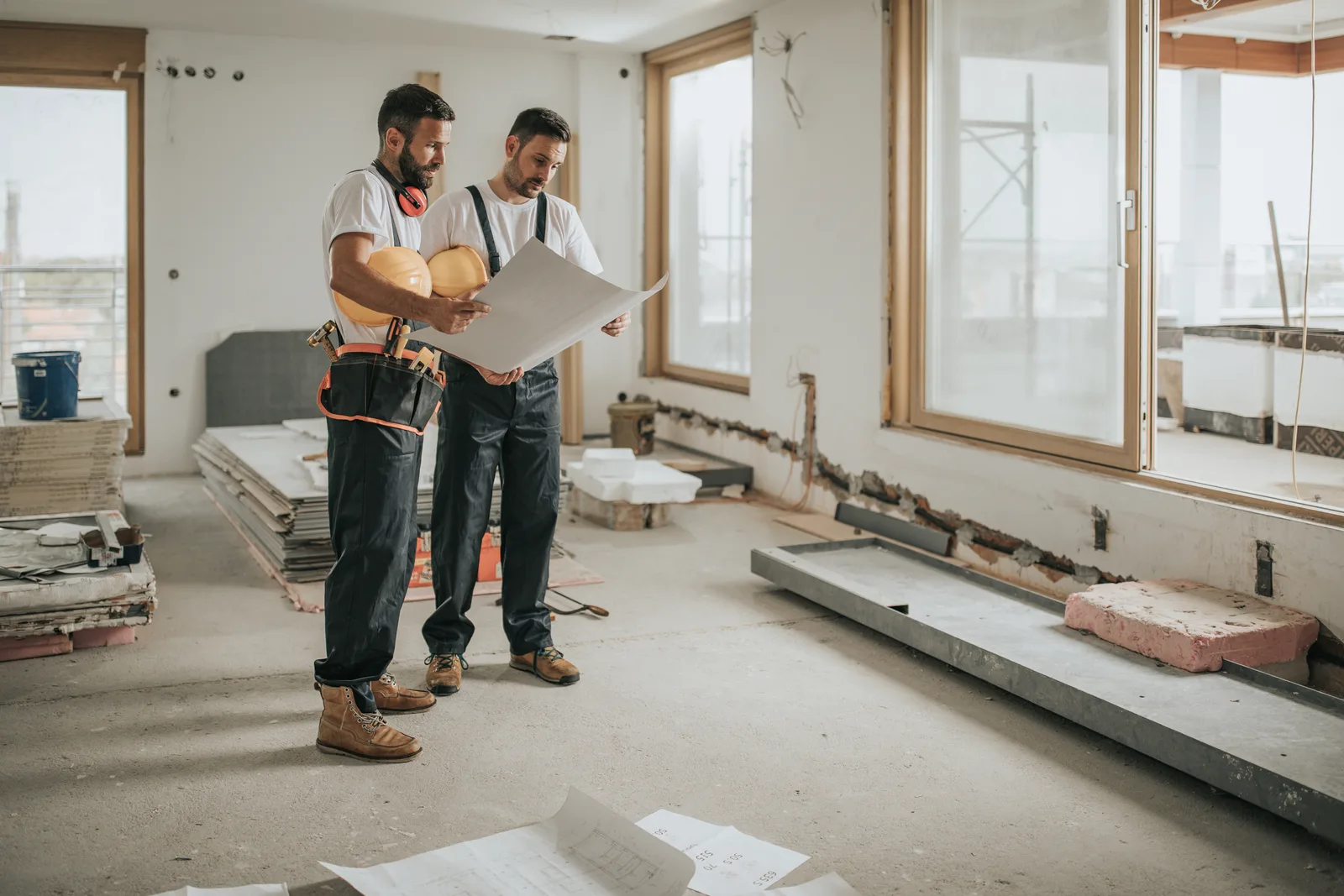 Two builders reviewing renovation drawings inside a commercial site