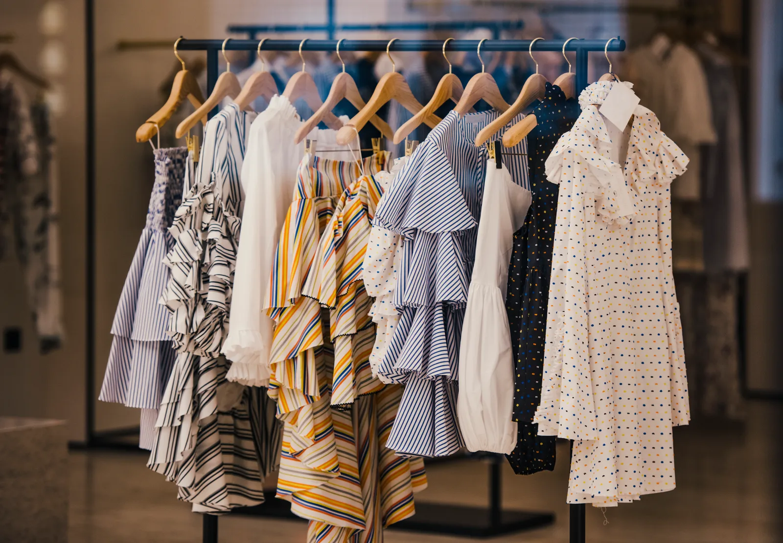 Boutique clothing rack with wooden hangers in a daylight-filled store